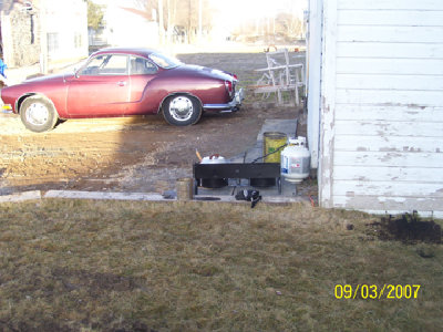 Another view of the set-up. Bucket #2, one of the roses I planted on the right, next to the shop and does anyone know what car that is?