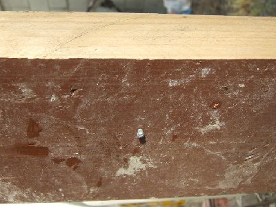 Close up of nail in wood after going through bottles.